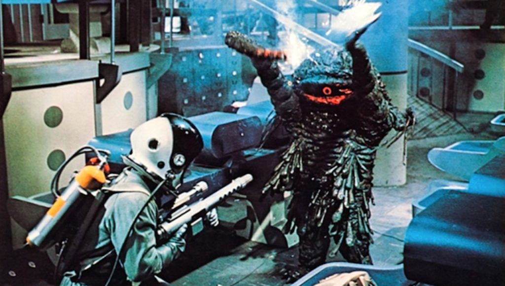 This is a film still from THE GREEN SLIME (1968) showing an astronaut being attacked by a murderous green tentacled space monster.