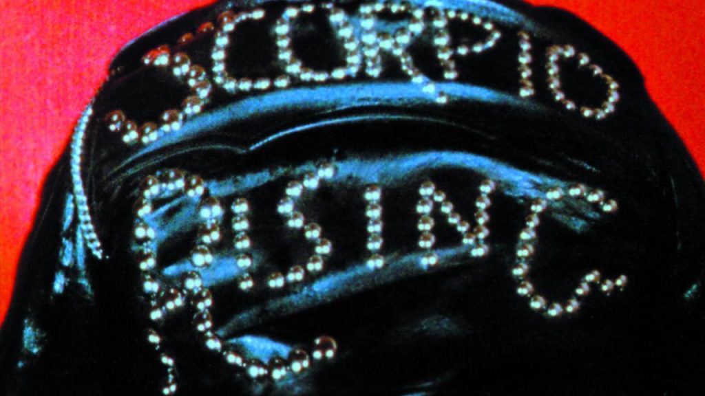 This is a film still from Kenneth Anger's SCORPIO RISING showing the film's title written in chrome studs on the back of black leather jacket.