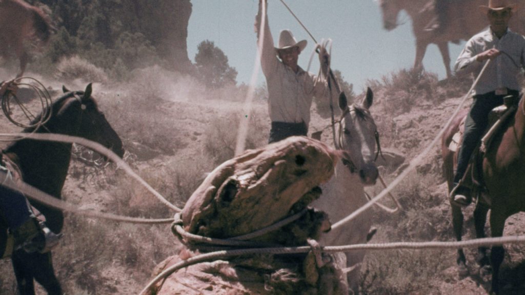 This is a film still from GODMONSTER OF INDIAN FLATS dir Fredric C. Hobbs (1973), showing a giant mutant sheep being lassooed by cowboys on horseback.
