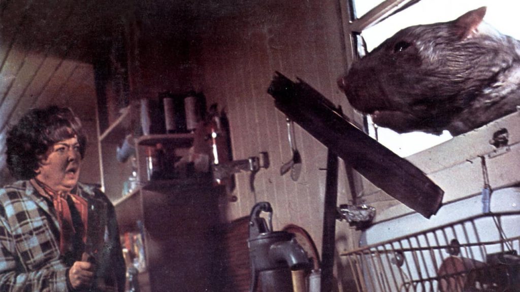 This is a film still from THE FOOD OF THE GODS dir Bert I Gordon (1976), showing a woman being terrorised by a giant rat that's bursting through her kitchen window.