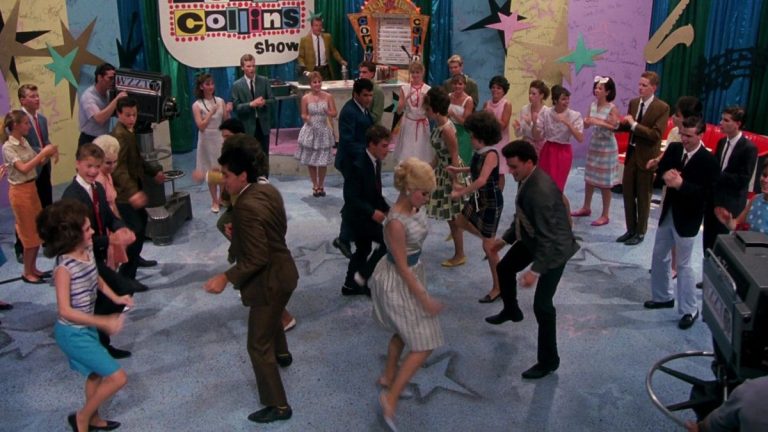 This is a film still from HAIRSPRAY dir John Waters (1988) showing a group of teenagers dancing the twist on the set of the 'Corny Collins' dance show.