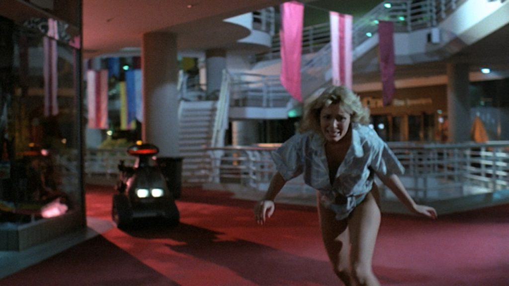 This is a film still from CHOPPING MALL dir Jim Wynorski (1986), showing at Beer Merchants Tap as part of CELLULOID JAM (Sun 16 March 2025).