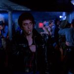 This is a film still from CRUISING dir William Friedkin (1980), showing the interior of a gay men's leather bar with Al Pacino at the centre of the image wearing a leather jacket and smoking a cigarette. Part of Halloween Double Bill at Rio Cinema (31 October 2025).